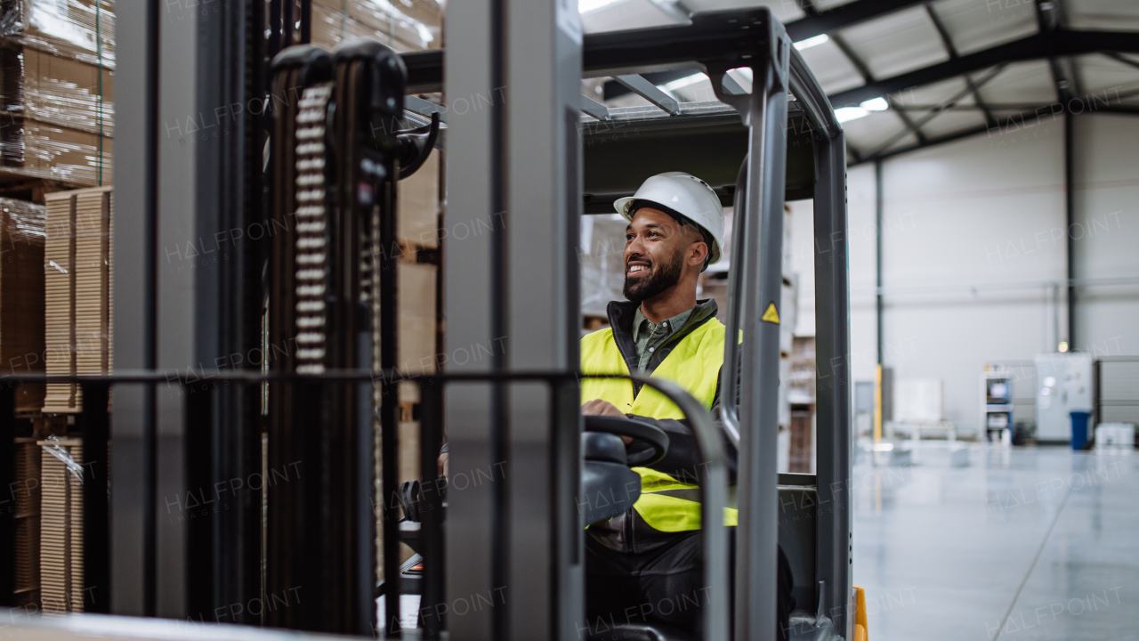 Portrait of multiracial warehouse worker driving forklift. Warehouse worker preparing products for shipmennt, delivery, checking stock in warehouse. Banner with copy space.