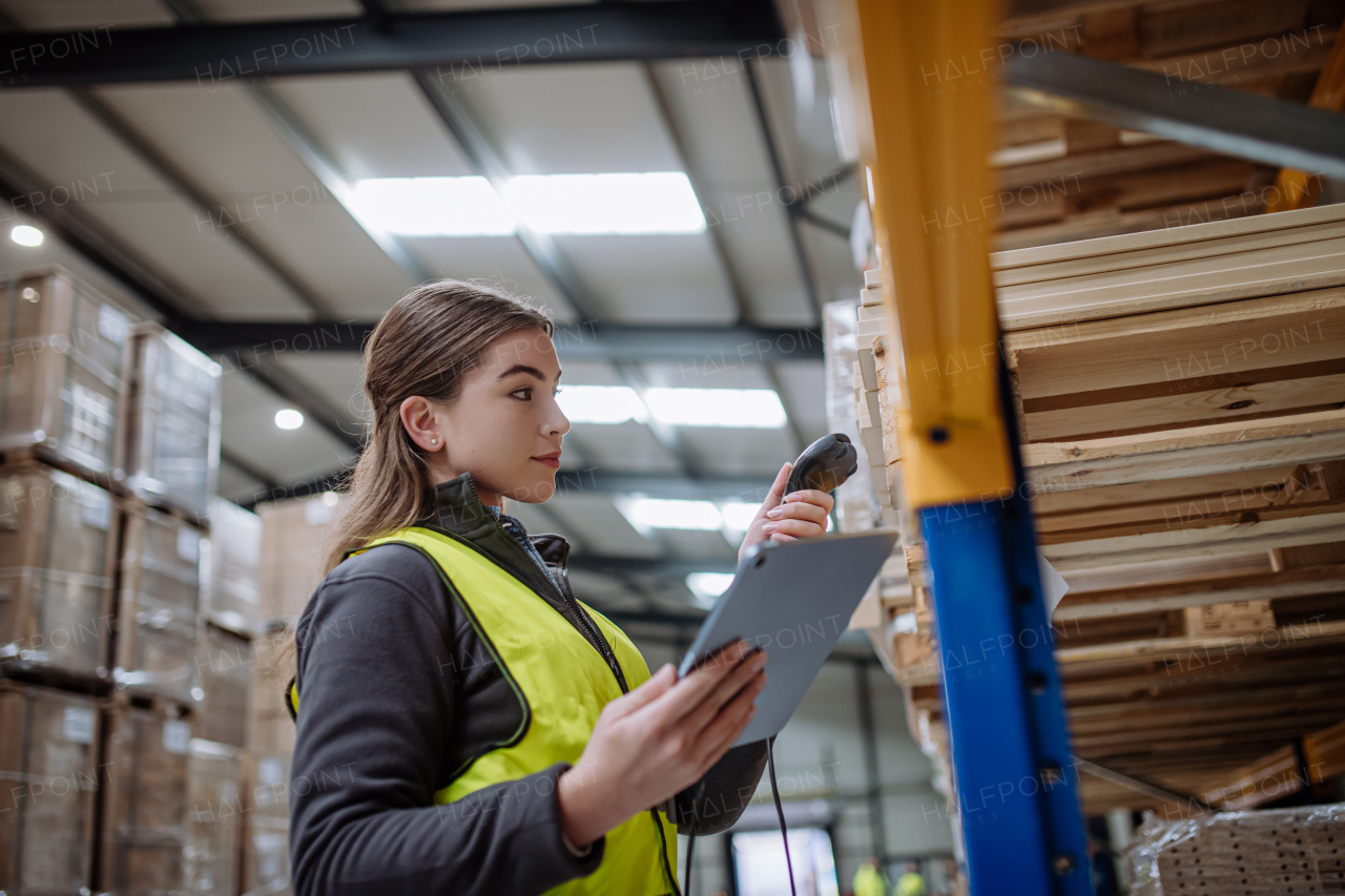 Female warehouse worker holding scanner and scanning the barcodes on products in warehouse. Warehouse manager using warehouse scanning system.