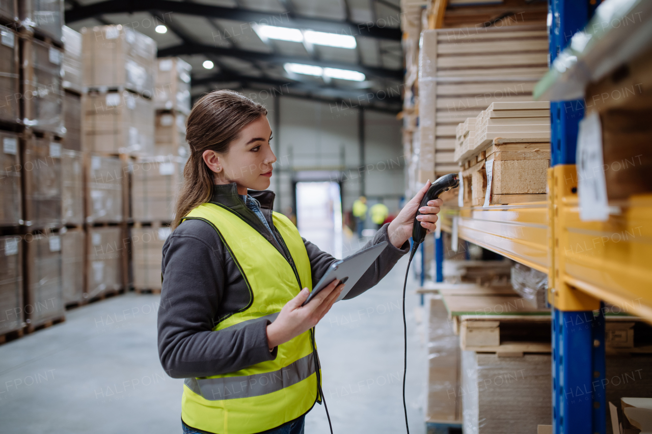 Female warehouse worker holding scanner and scanning the barcodes on products in warehouse. Warehouse manager using warehouse scanning system.