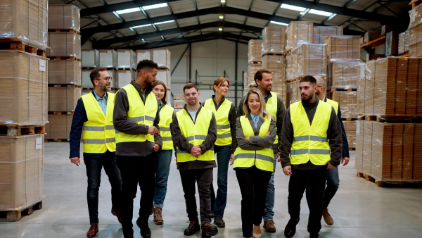 Full team of warehouse employees standing in warehouse. Team of workers in modern industrial factory, heavy industry, manufactrury.