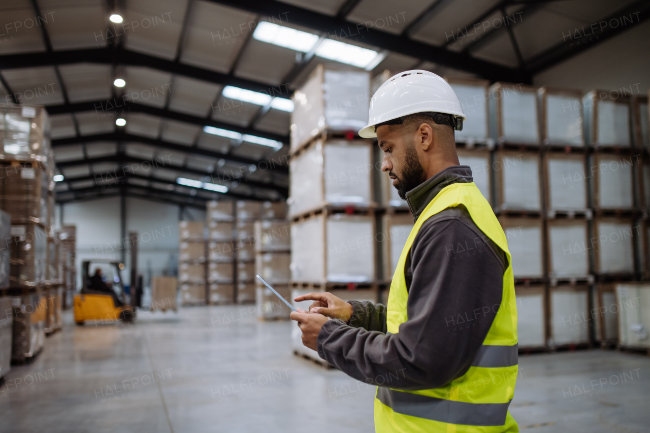 Portrait of warehouseman with tablet checking delivery, stock in warehouse. Warehouse manager using warehouse management software, app.