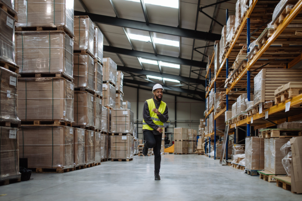 Warehouseman with tablet helmet dancing in the middle of the warehouse. Warehouse working having fun at work.