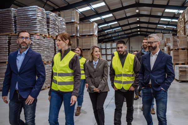 Full team of warehouse employees standing in warehouse. Team of workers, managers and female director in modern industrial factory, heavy industry, manufactrury. Group portrait.