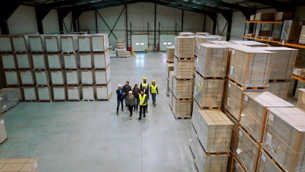 Top view of full team of warehouse employees walking in warehouse. Team of workers, managers and female director in modern industrial factory, heavy industry, manufactrury. Group portrait.