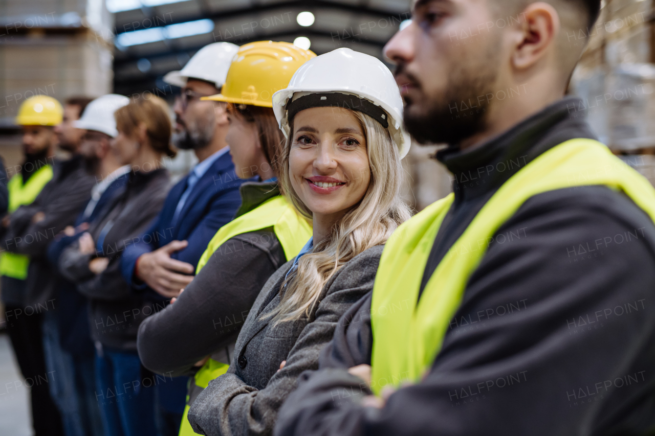 Full team of warehouse employees standing in warehouse. Team of workers in reflective clothing in modern industrial factory, heavy industry, manufactrury. Group portrait.