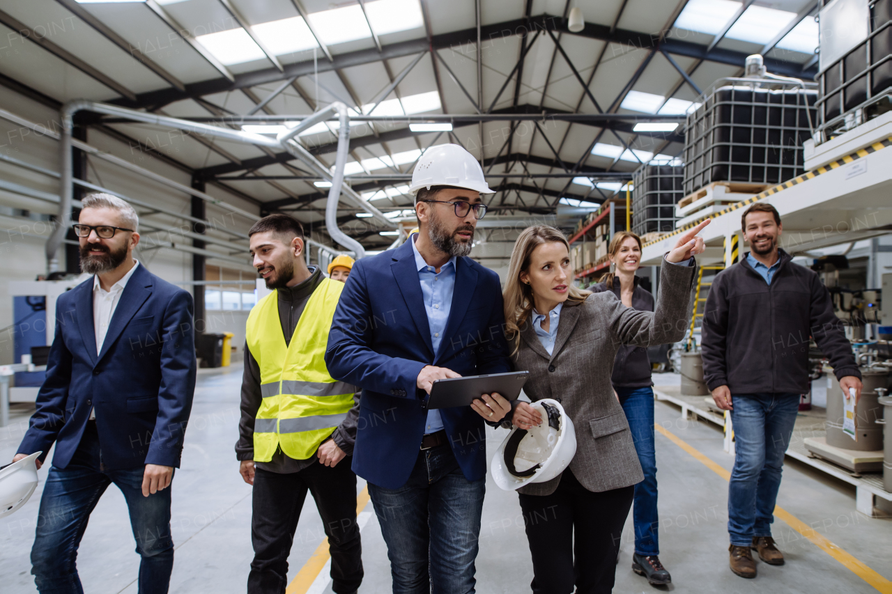 Full team of warehouse employees walking in warehouse. Team of workers, managers and female director in modern industrial factory, heavy industry, manufactrury. Group portrait.