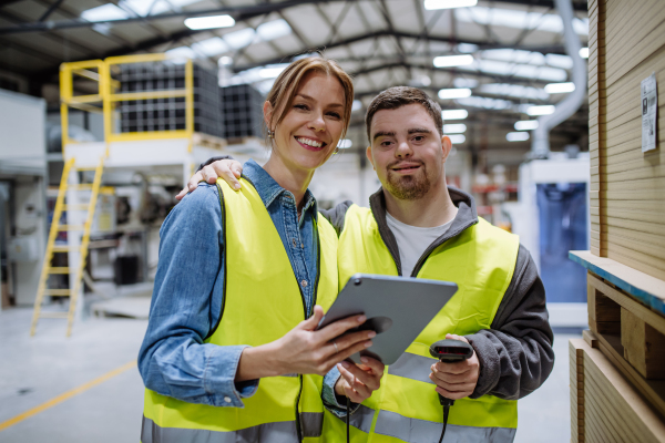 Young man with Down syndrome working in warehouse, female colleague teaching him how to scan products with scanner. Concept of workers with disabilities, support in workplace.