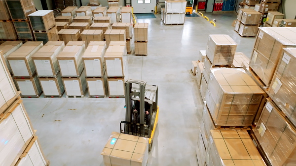 A top view of warehouse worker driving forklift. Warehouse worker preparing products for shipmennt, delivery, checking stock in warehouse.