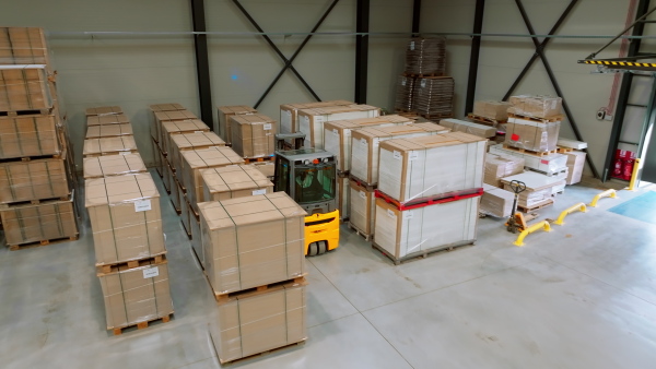 A top view of warehouse worker driving forklift. Warehouse worker preparing products for shipmennt, delivery, checking stock in warehouse.