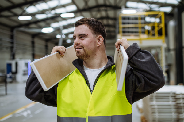 Young man with Down syndrome working in warehouse. Concept of workers with disabilities, support in workplace.