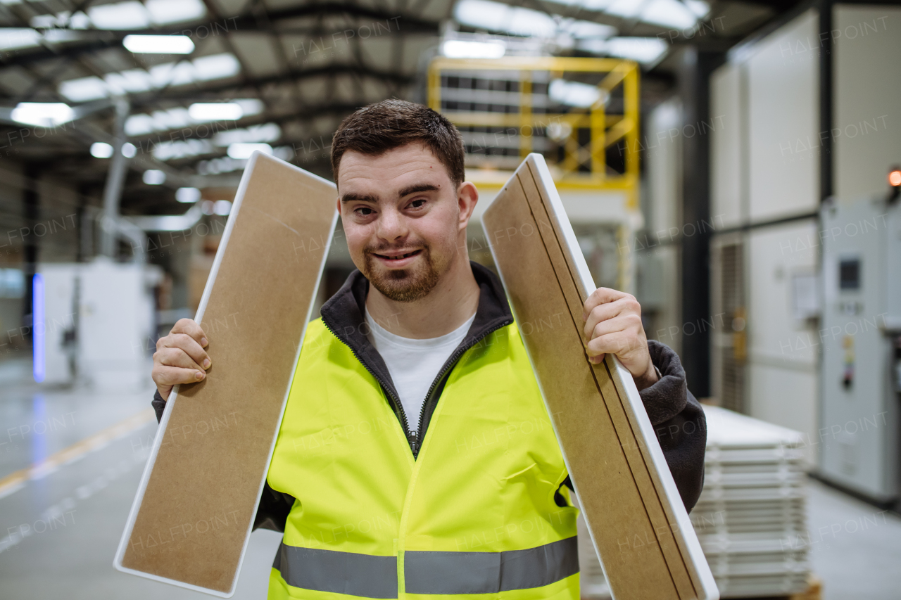 Young man with Down syndrome working in warehouse. Concept of workers with disabilities, support in workplace.