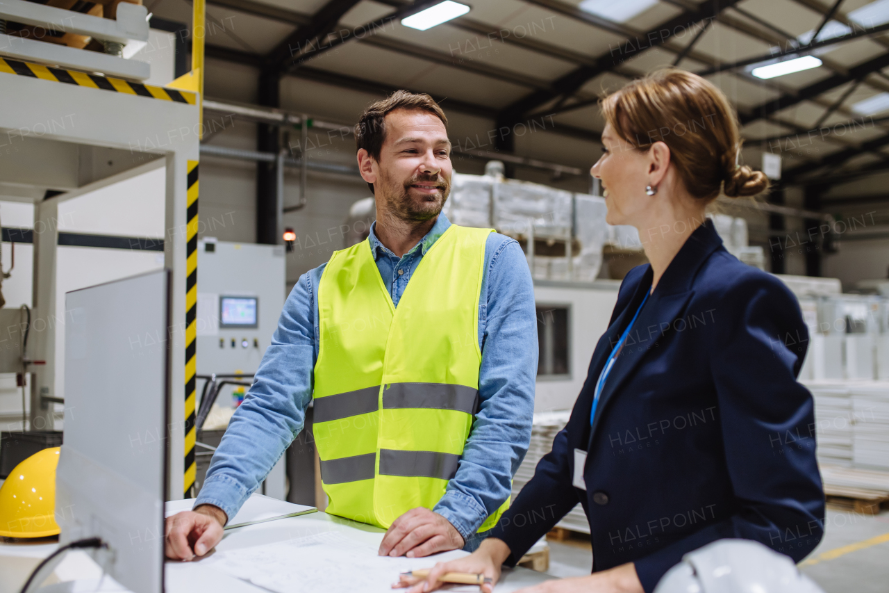 Female warehouse director talking with production manager, discussing new order, preparing products for shipmennt, delivery, checking stock in the warehouse.