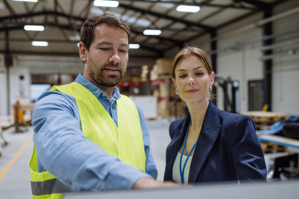 Female warehouse director talking with production manager, discussing new order, preparing products for shipmennt, delivery, checking stock in the warehouse.