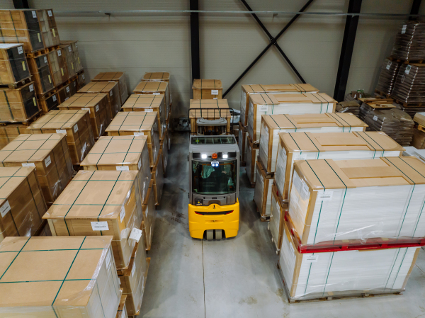 Top view of forklift in warehouse in the middle of stored goods. Forklift driver preparing products for shipmennt, delivery, checking stock in the warehouse.