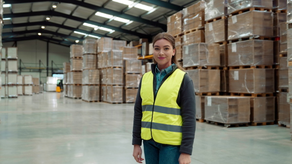 Video of female warehouse worker standing in warehouse. Warehouse manager checking delivery, stock in warehouse, inspecting products for shipment.