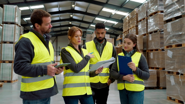 Full team of warehouse employees standing in warehouse. Team of workers in reflective clothing in modern industrial factory, heavy industry, manufactrury. Group video.