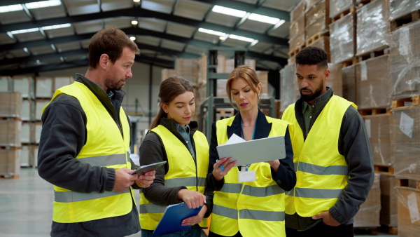 Full team of warehouse employees standing in warehouse. Team of workers in reflective clothing in modern industrial factory, heavy industry, manufactrury. Group video.