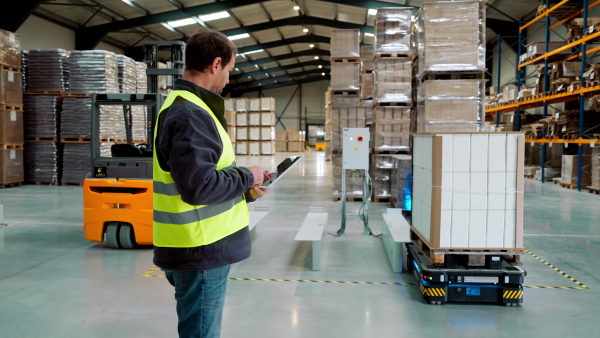 Video of warehouseman with tablet checking delivery, stock in warehouse. Warehouse manager using warehouse management software, app.