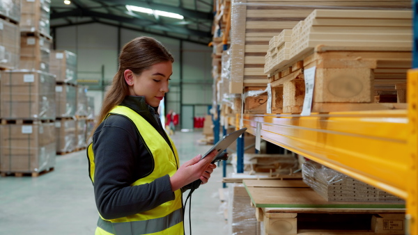 Female warehouse worker holding scanner and scanning the barcodes on products in warehouse. Warehouse manager using warehouse scanning system.