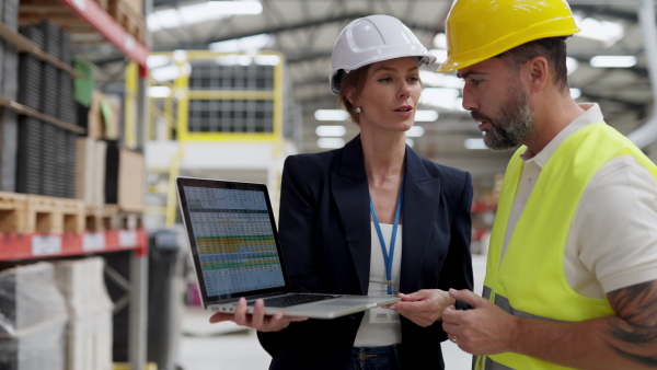 Female warehouse director talking with production manager, discussing new order, preparing products for shipmennt, delivery, checking stock in the warehouse.