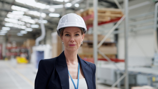 A female warehouse director standing in warehouse and looking at camera.