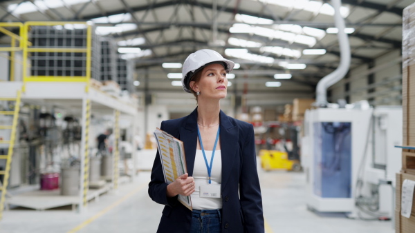 A female warehouse director in warehouse. Warehouse manager checking delivery, stock in warehouse, inspecting products for shipment.