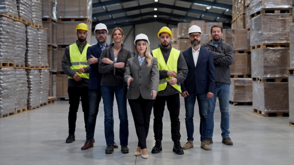 Full team of warehouse employees standing in warehouse. Team of workers in modern industrial factory, heavy industry, manufactrury.