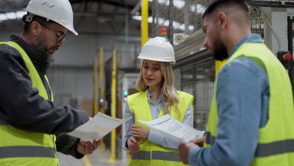 Engineers consulting with director in modern industrial factory, talking about new production project, investment. Team management in manufacturing facility.