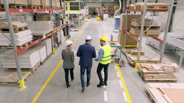 Top view of engineers consulting with director in modern industrial factory, talking about new production project, investment. Team management in manufacturing facility.