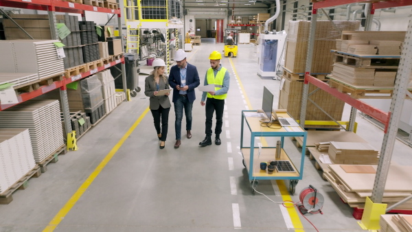 Top view of engineers consulting with director in modern industrial factory, talking about new production project, investment. Team management in manufacturing facility.