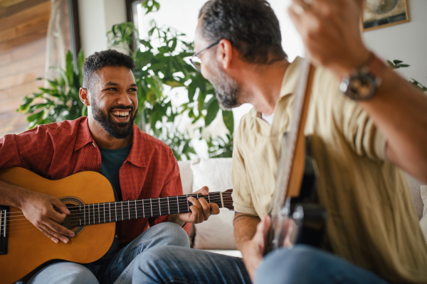 Best friends, musician jamming together. Playing music on acoustic and electric guitar together, having fun. Concept of male friendship, bromance.