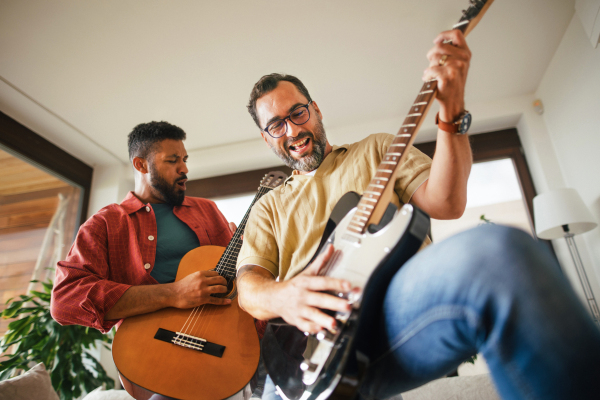 Best friends, musician jamming together. Playing music on acoustic and electric guitar together, having fun. Concept of male friendship, bromance.