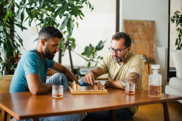 Best friends playing chess together, drinking whiskey and talking. Concept of male friendship and bromance.