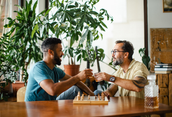 Best friends playing chess together, drinking whiskey and talking. Concept of male friendship and bromance.