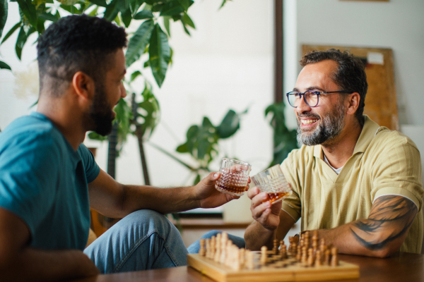 Best friends playing chess together, drinking whiskey and talking. Concept of male friendship and bromance.