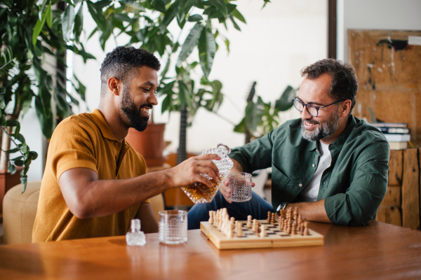 Best friends playing chess together, drinking whiskey and talking. Concept of male friendship and bromance.