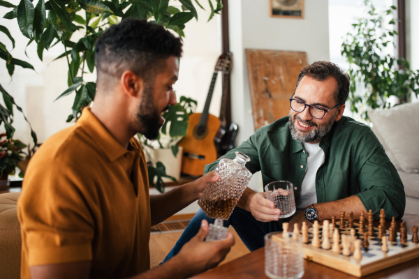 Best friends playing chess together, drinking whiskey and talking. Concept of male friendship and bromance.