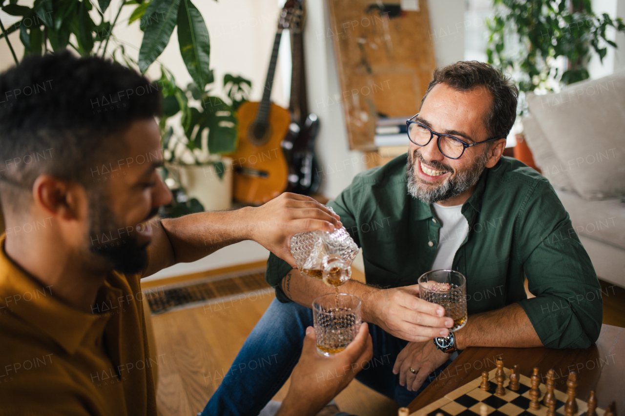 Best friends playing chess together, drinking whiskey and talking. Concept of male friendship and bromance.