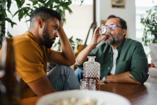 Best friends, supporting each other, drinking whiskey and talking. Discussing problems and drowning sorrows in alcohol. Concept of male friendship and bromance.