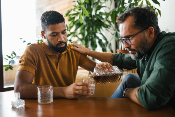 Best friends, supporting each other, drinking whiskey and talking. Discussing problems and drowning sorrows in alcohol. Concept of male friendship and bromance.