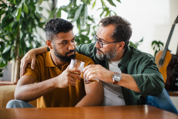 Best friends, supporting each other, drinking whiskey and talking. Discussing problems and drowning sorrows in alcohol. Concept of male friendship and bromance.