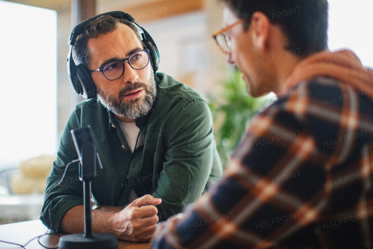 Male friends doing video podcast, talking about difficult topics, sharing sad, hurtful stories. Influencers making live video for social media, creating online content at home.