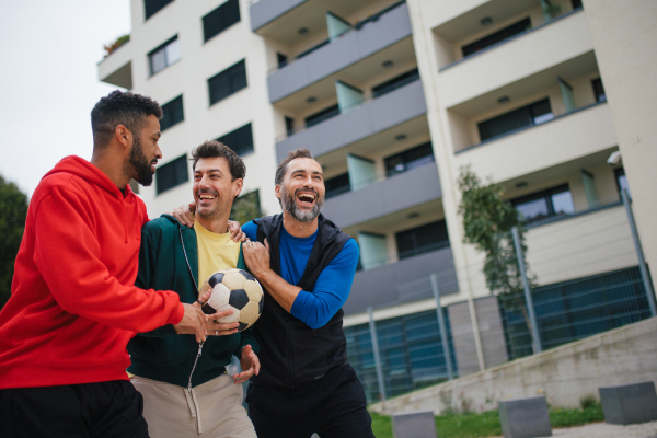 Best friends playing sport outdoors, having fun, competing. Playing football at the local field, enjoying exercise together. Concept of male friendship, bromance.