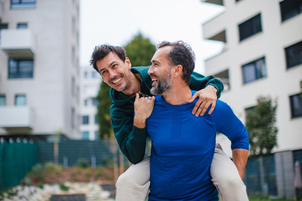 Best friends playing sport outdoors, having fun. Celebratin goal, carrying friend on back, piggybacking. Concept of male friendship, bromance.