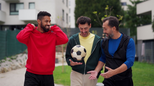 Best friends playing sport outdoors, having fun, competing. Playing football at a local pitch, enjoying exercise together. Concept of male friendship, bromance.