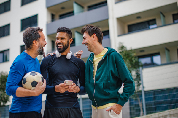 Best friends playing sport outdoors, having fun, competing. Playing football at the local field, enjoying exercise together. Concept of male friendship, bromance.