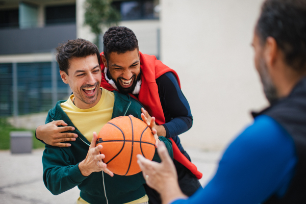 Best friends playing sport outdoors, having fun, competing. Playing basketball at local court, enjoying exercise together. Concept of male friendship, bromance.