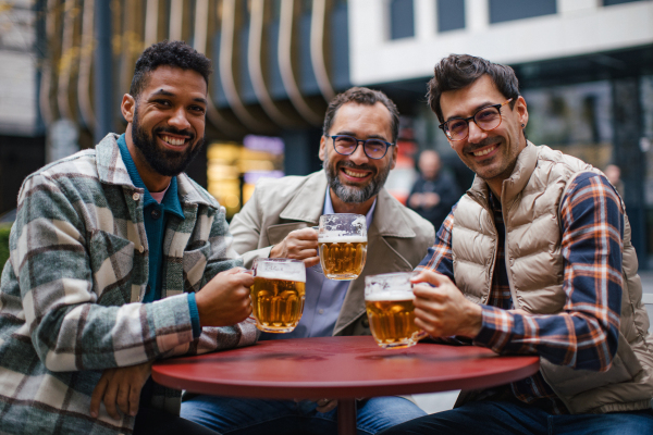 Best friends togehter, drinking beer in bar in the city and talking, having fun and laugh. Concept of male friendship, bromance.