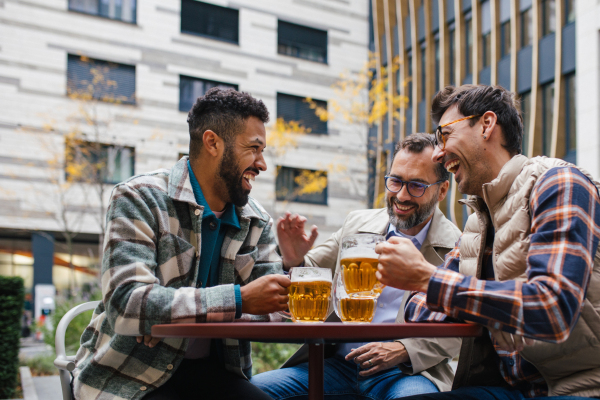 Best friends togehter, drinking beer in bar in the city and talking, having fun and laugh. Concept of male friendship, bromance.