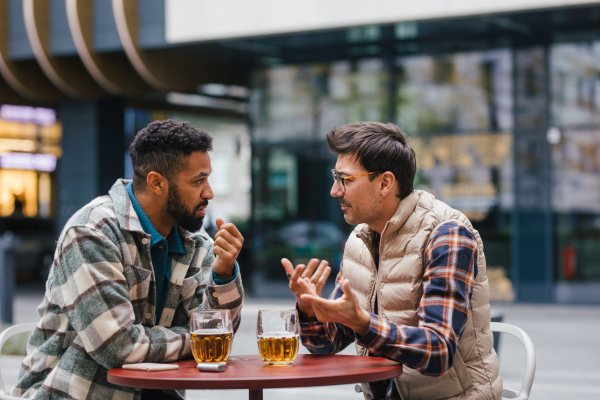 Best friends togehter, drinking beer in bar in the city and talking, having fun and laugh. Concept of male friendship, bromance.